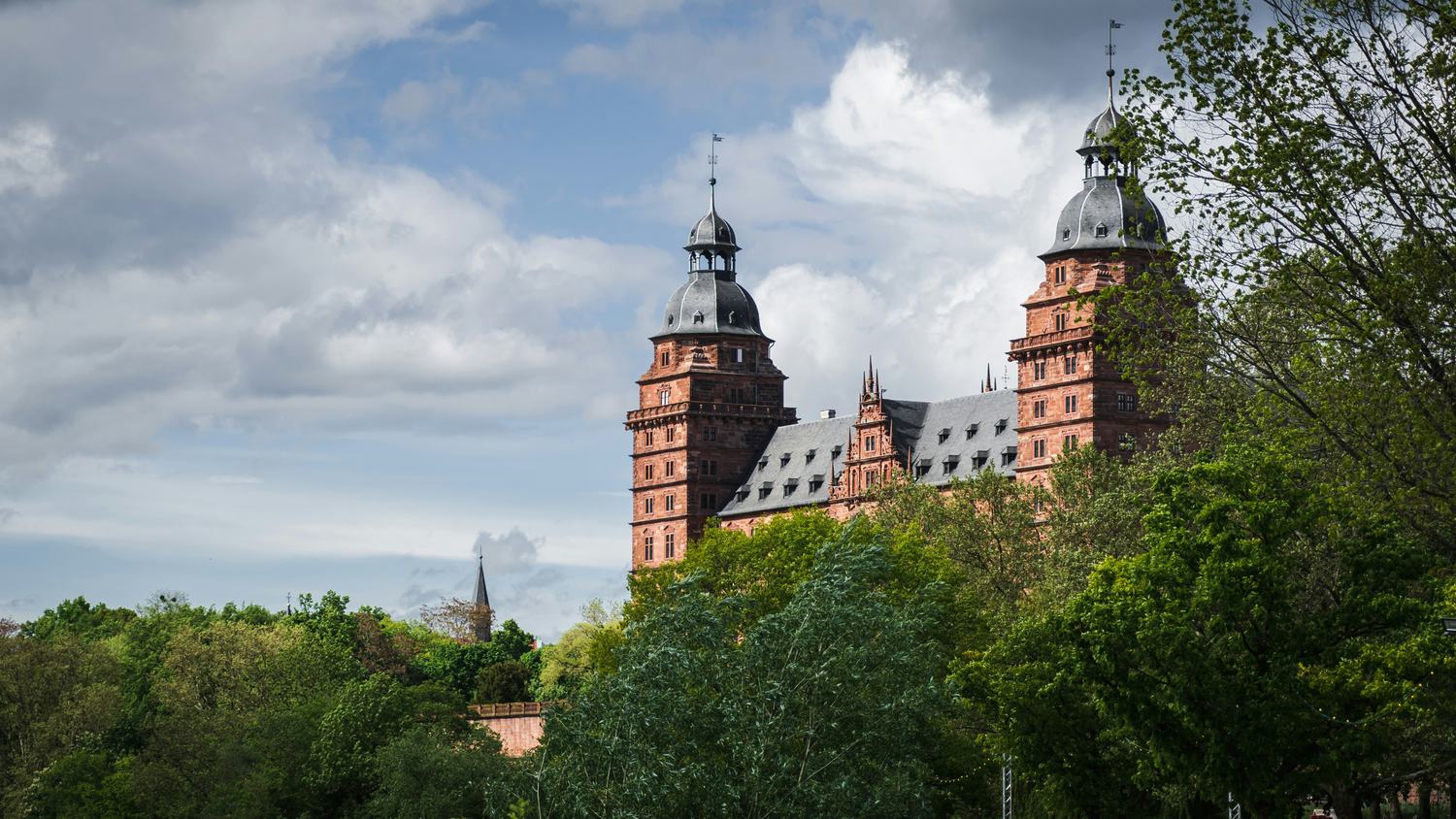 Schloss Johannisburg in Aschaffenburg über den Baumkronen des Schlossparks